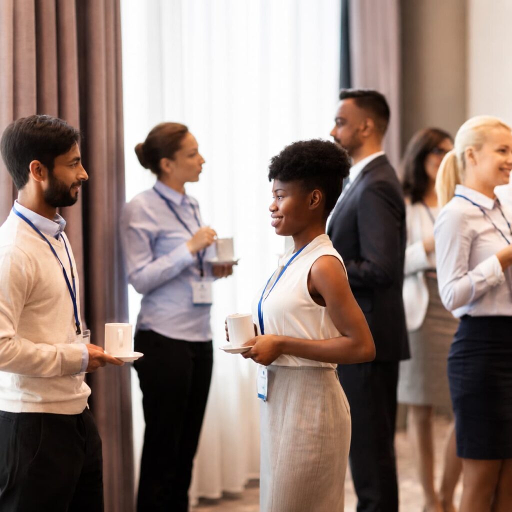 A diverse group of professional business conference attendees networking and talking during a coffee break at Ein Gedi Premier.